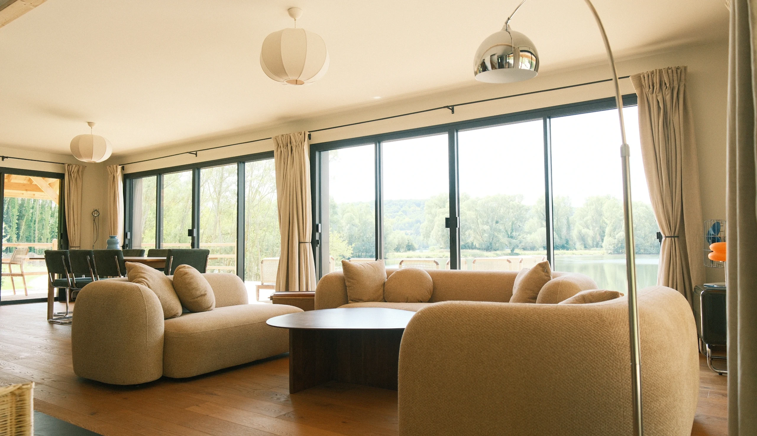 Dining and living area of the Canadian House, large central sofa, floor-to-ceiling windows with nature view