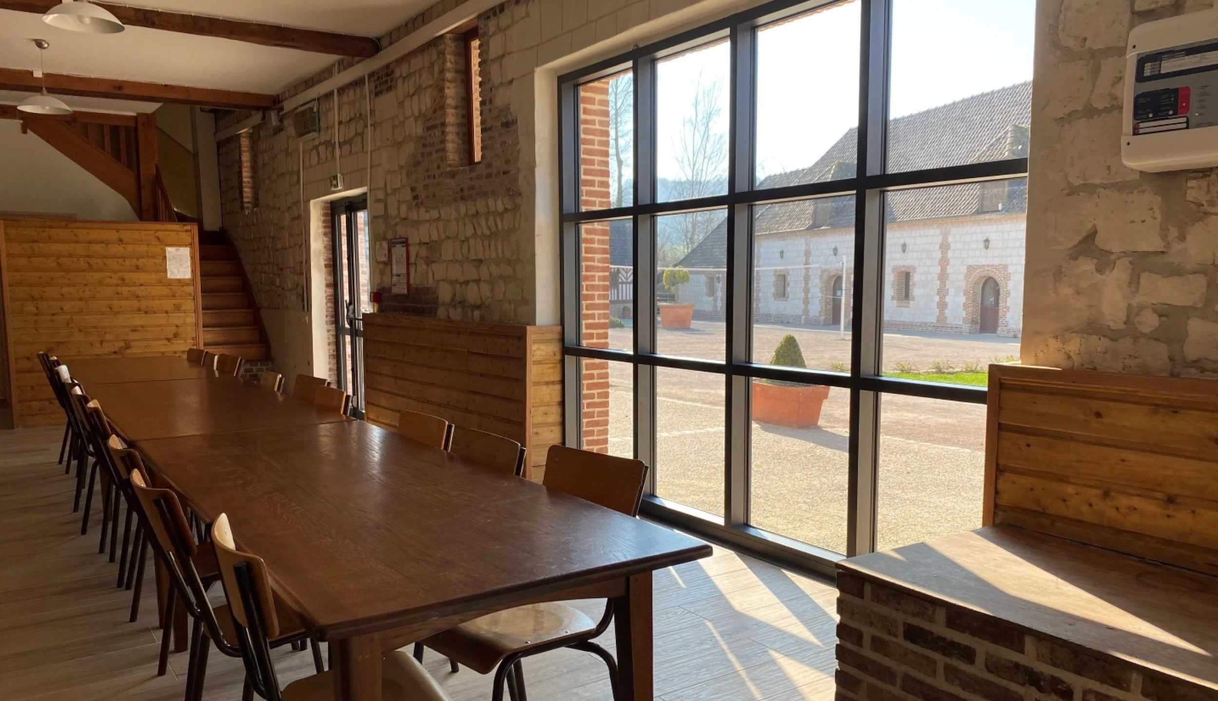 Dining room with long table, large bay window, stone wall