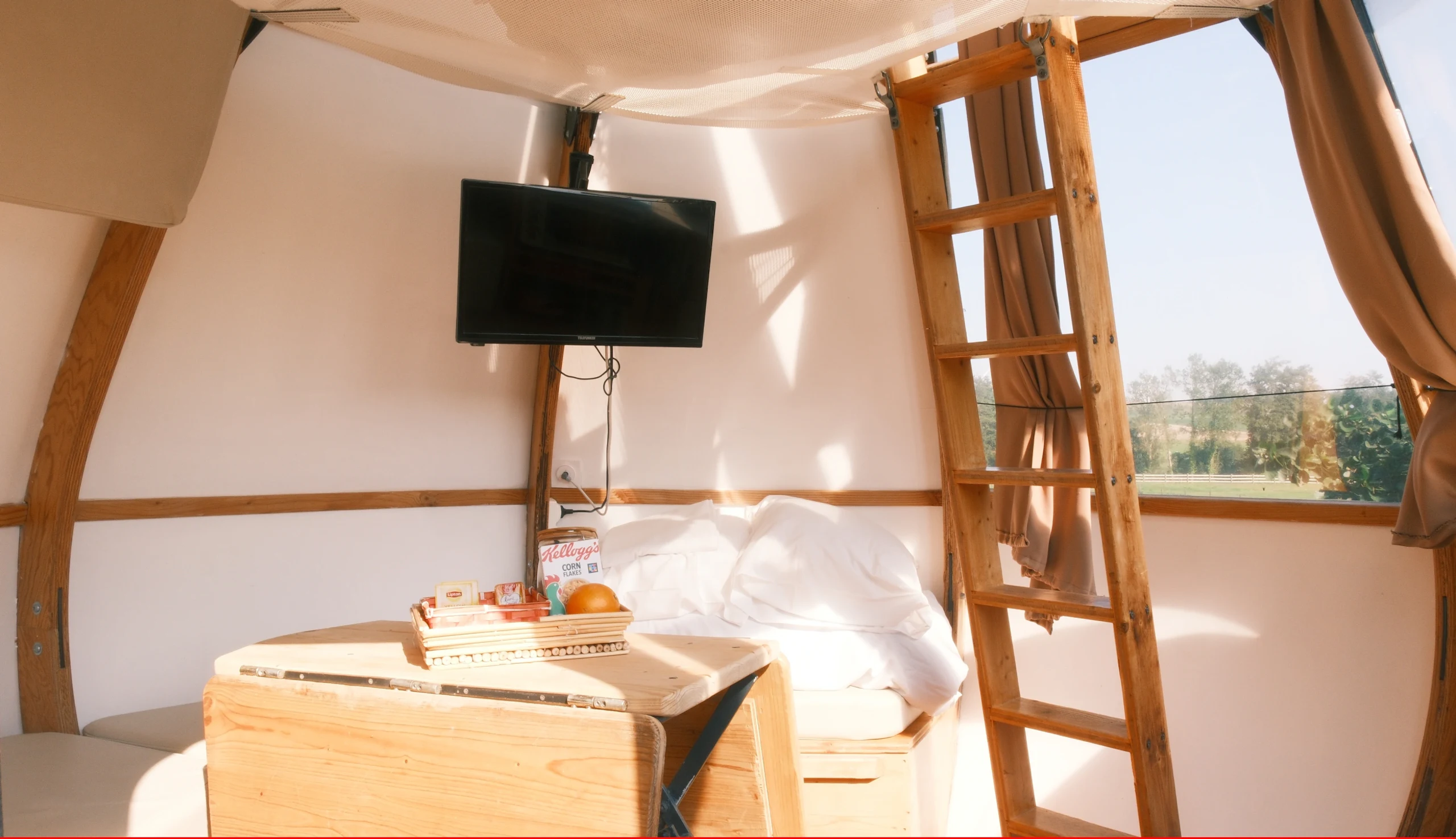 Interior of the Goutte d’Ô, wooden ladder, wall-mounted television, window overlooking the outdoors