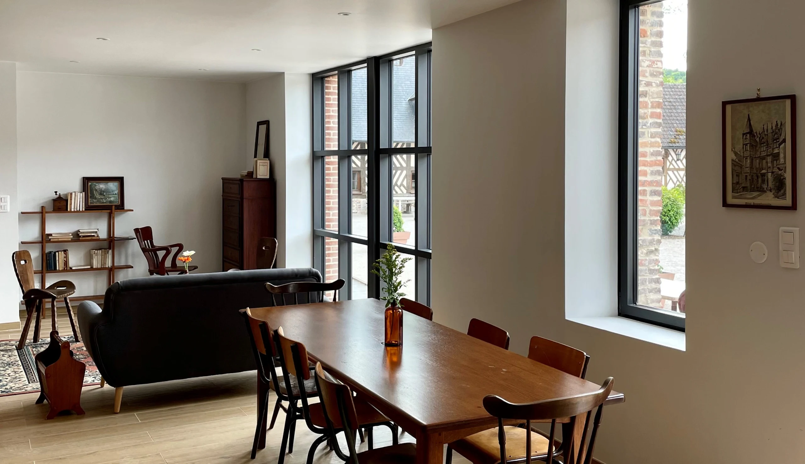Living room with sofa, large wooden table, a window and a glass door