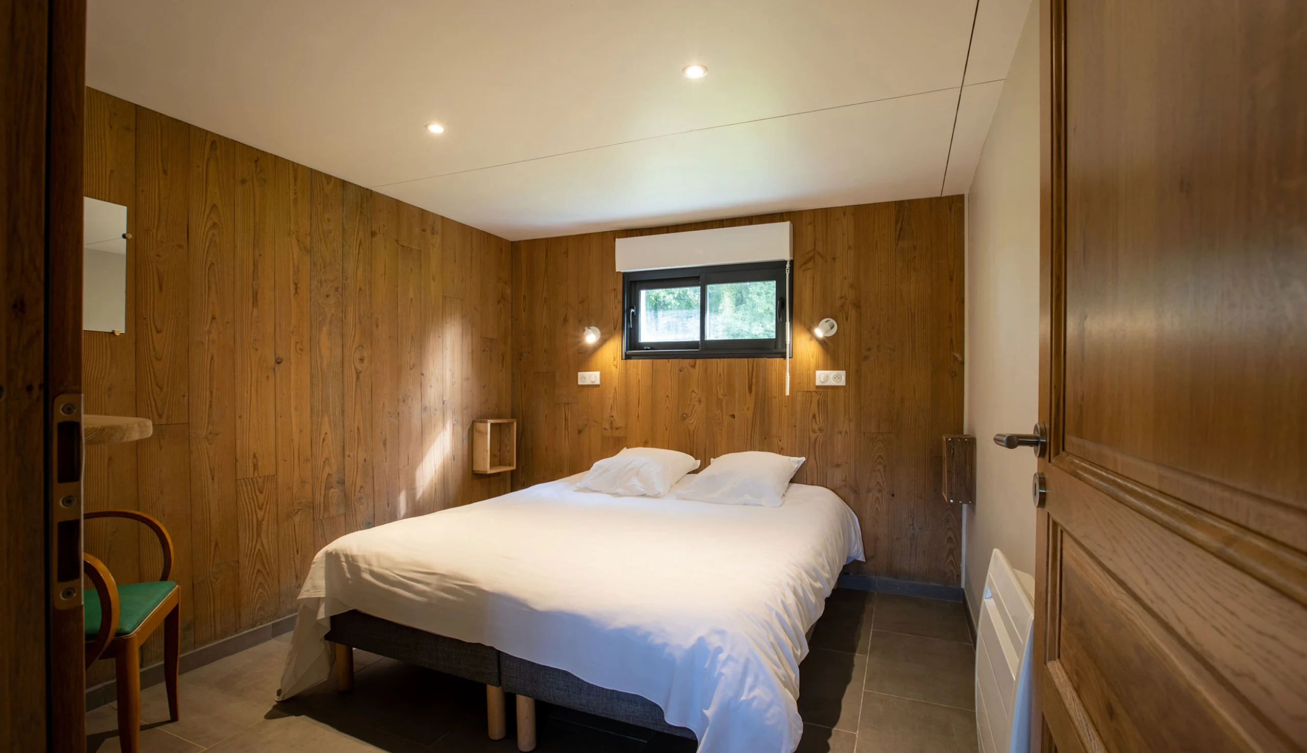 Bedroom with double bed, wooden walls, and window