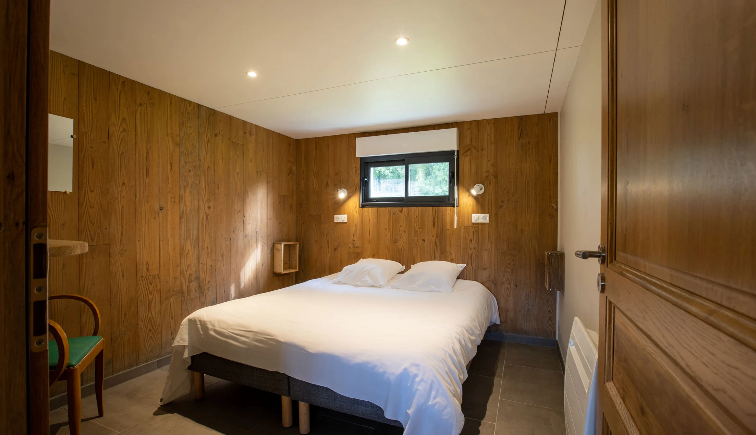 Bedroom with double bed, wooden walls, and window