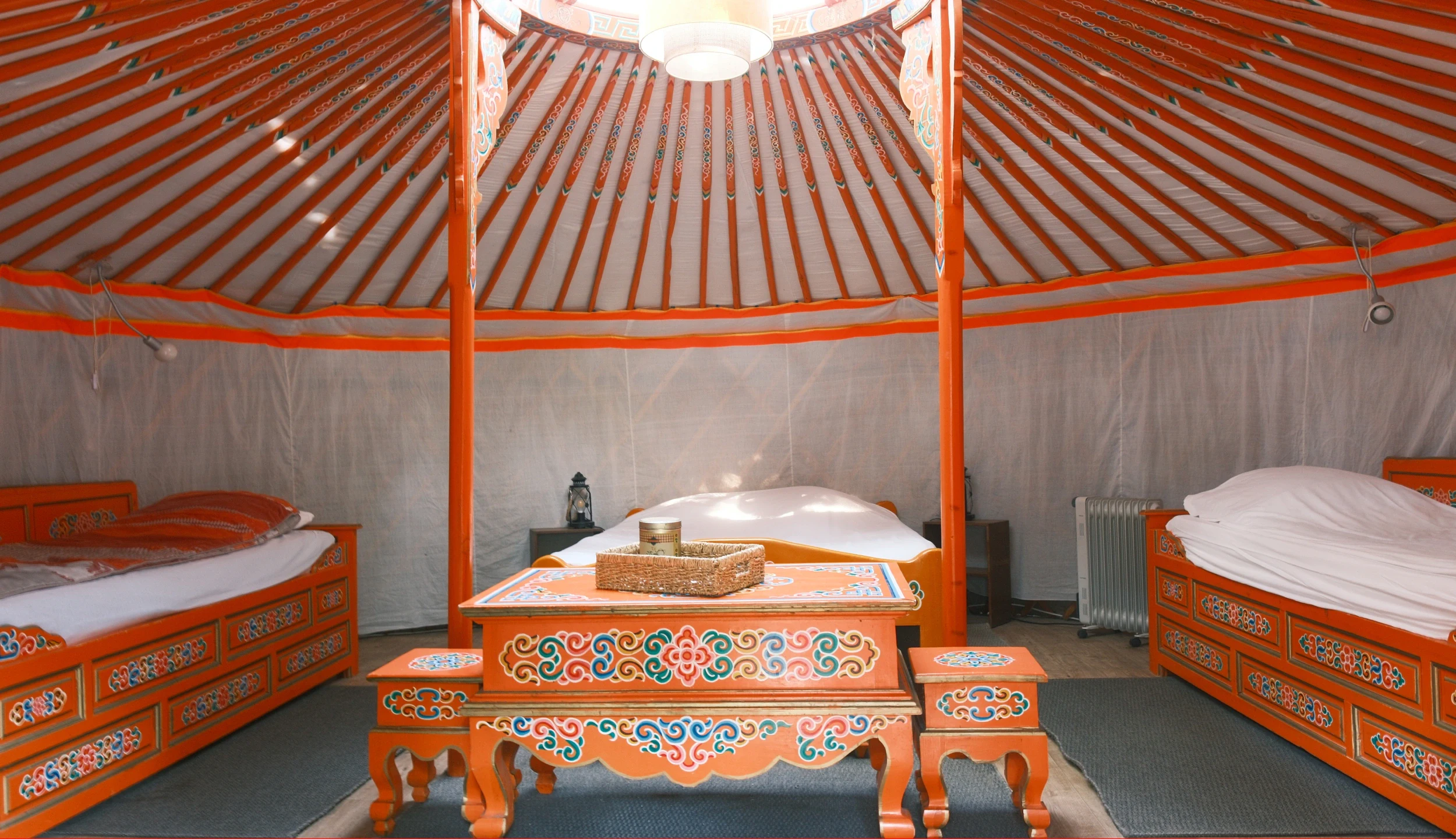 Interior of the yurt, two single beds that can also be used as benches, a low table in the centre
