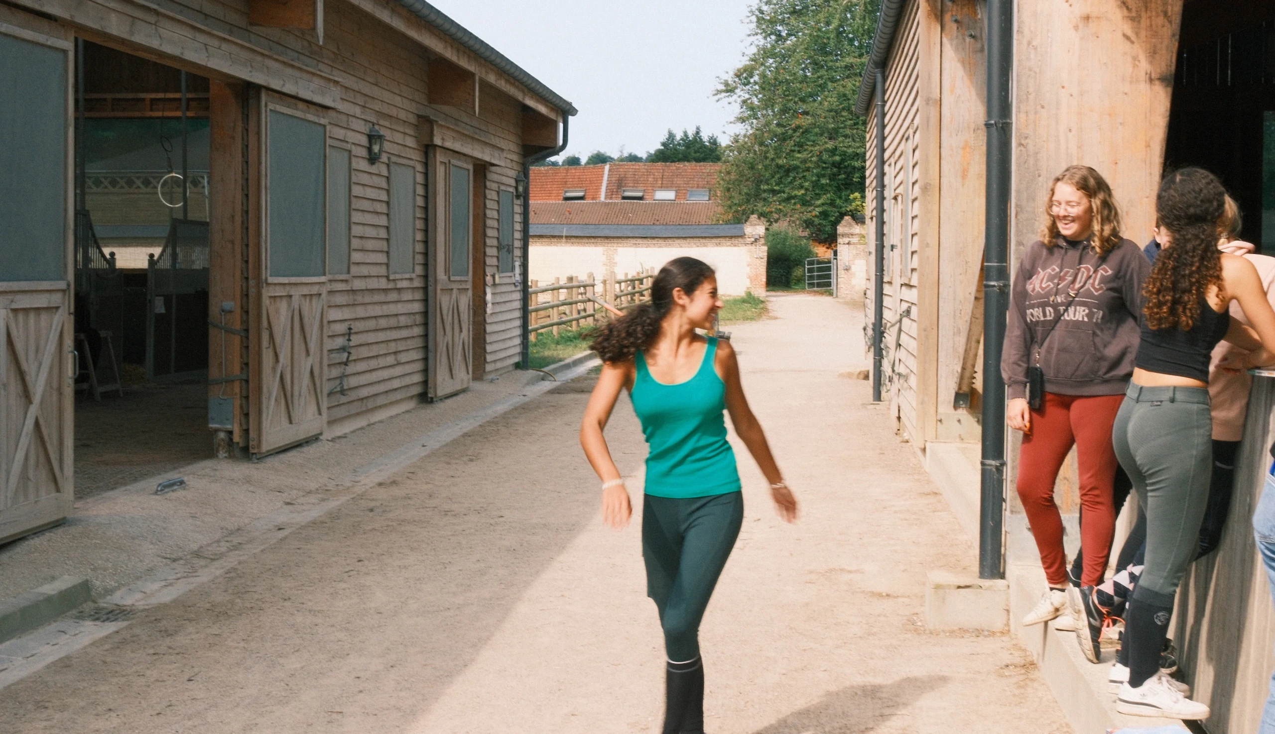 Smiling young riders in front of the wooden stables