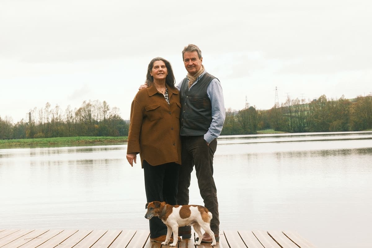 Jérôme Maillard et Marie-Annick de Thézy debout avec leur chien devant un des étangs du domaine.