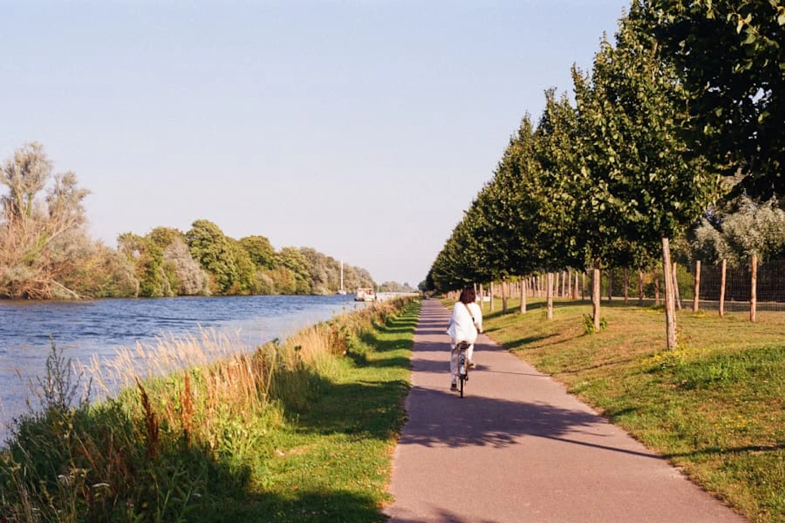 A woman is cycling along a road by the Somme River