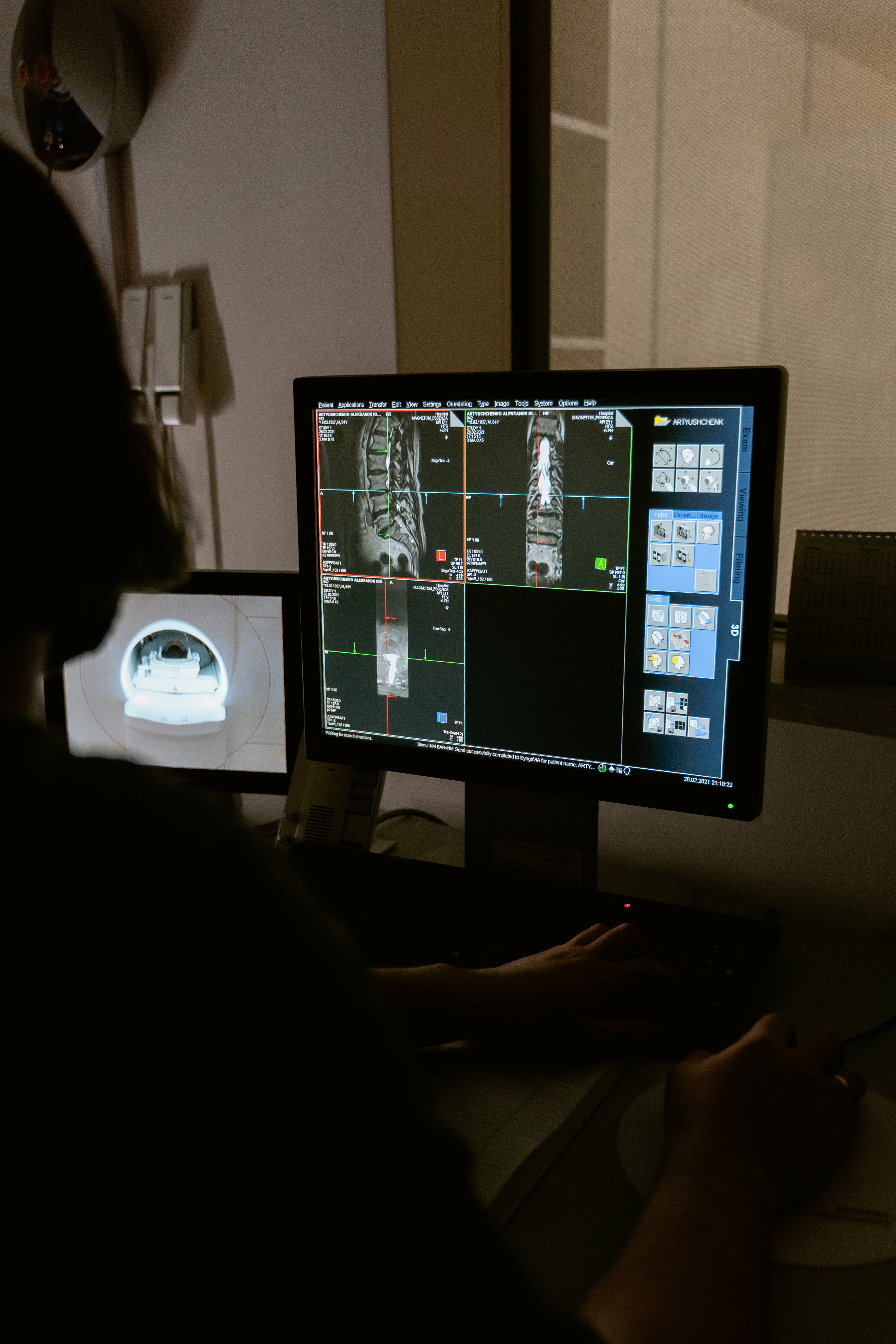 Person looks at two monitors one showing results of a CT scan and the other showing a video feed of the machine