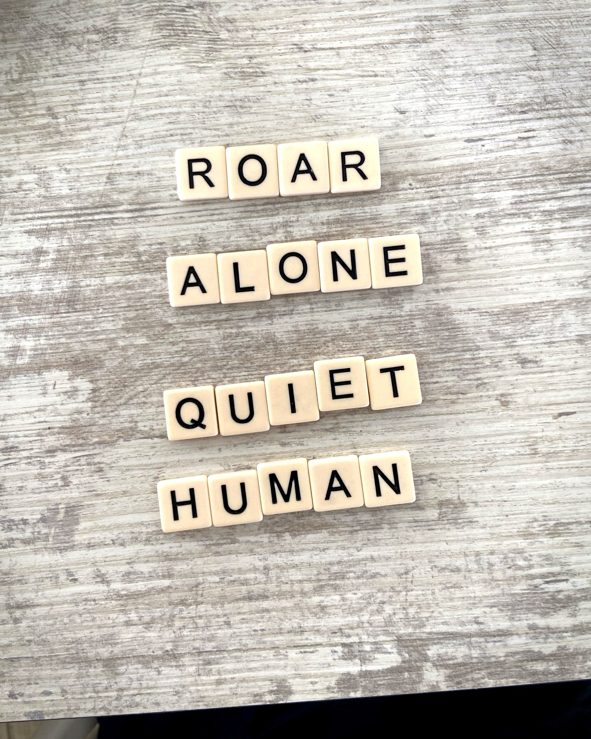 Scrabble letters reading Roar Alone Quiet Human