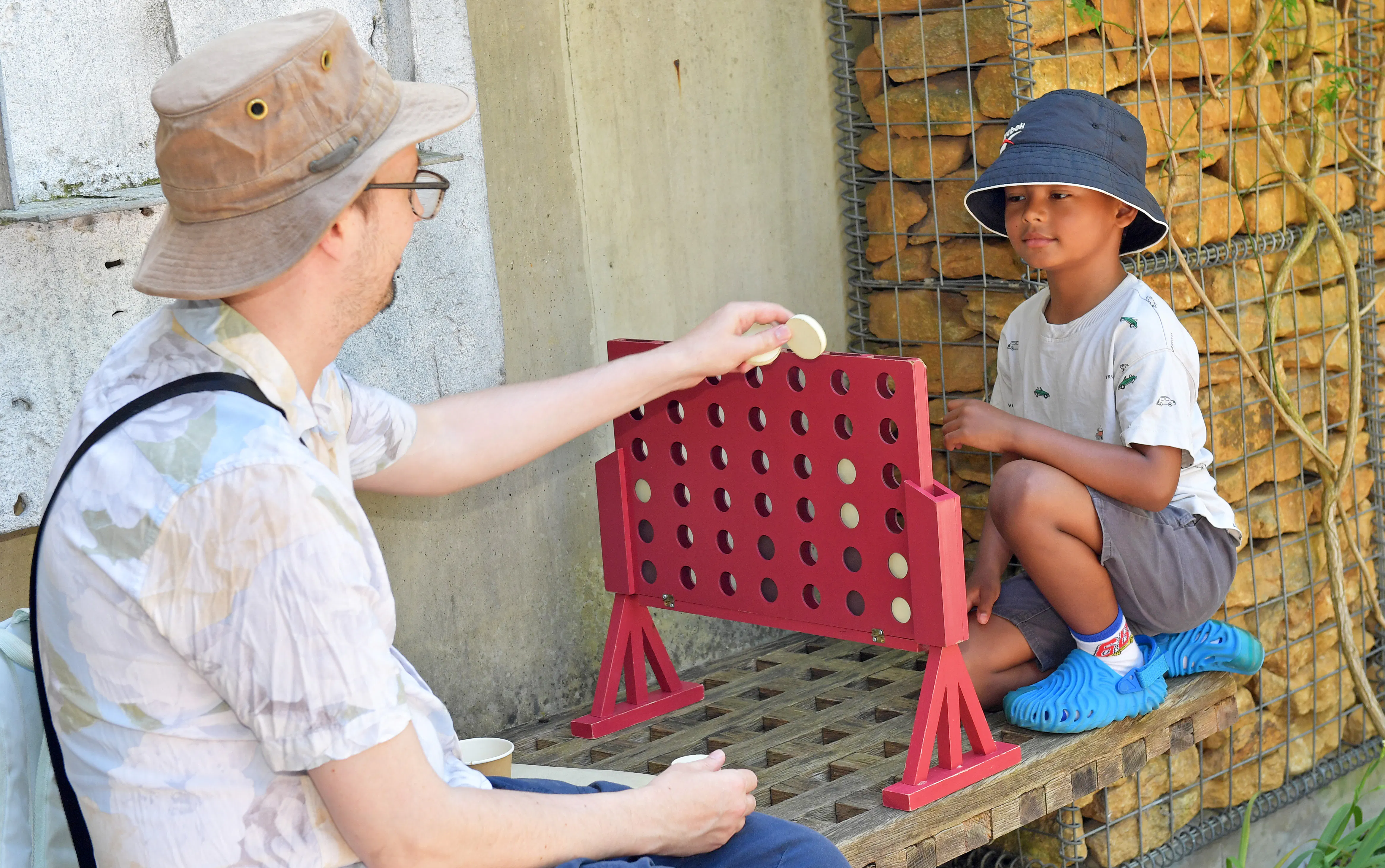 shows an adult and child playing an outdoor game of connect four