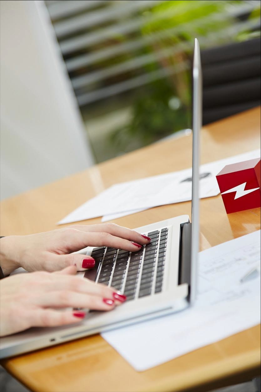 Mitarbeiterin arbeitet am Laptop mit Lightpower Logo, Büroarbeitsplatz im Unternehmen für Bühnentechnik