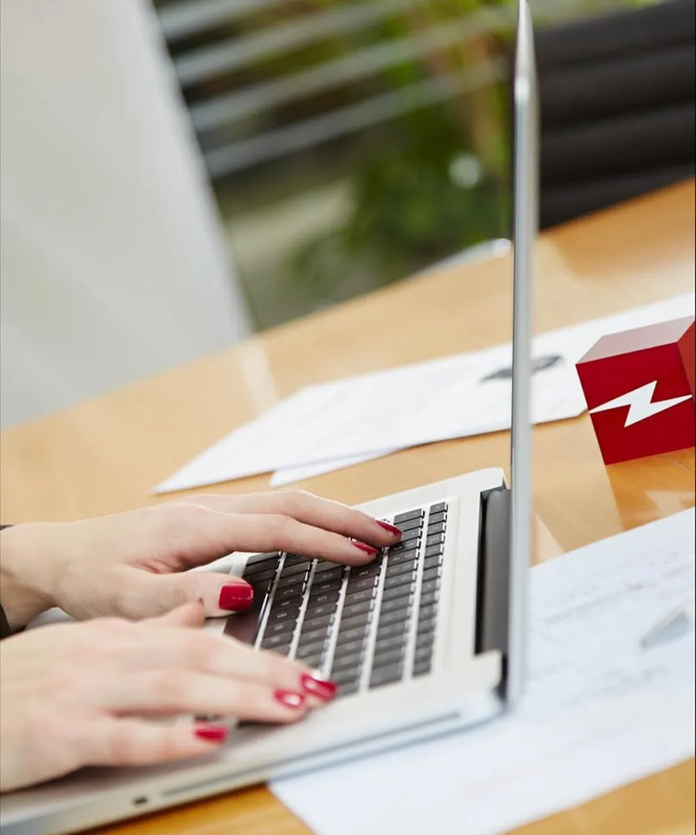 Mitarbeiterin arbeitet am Laptop mit Lightpower Logo, Büroarbeitsplatz im Unternehmen für Bühnentechnik