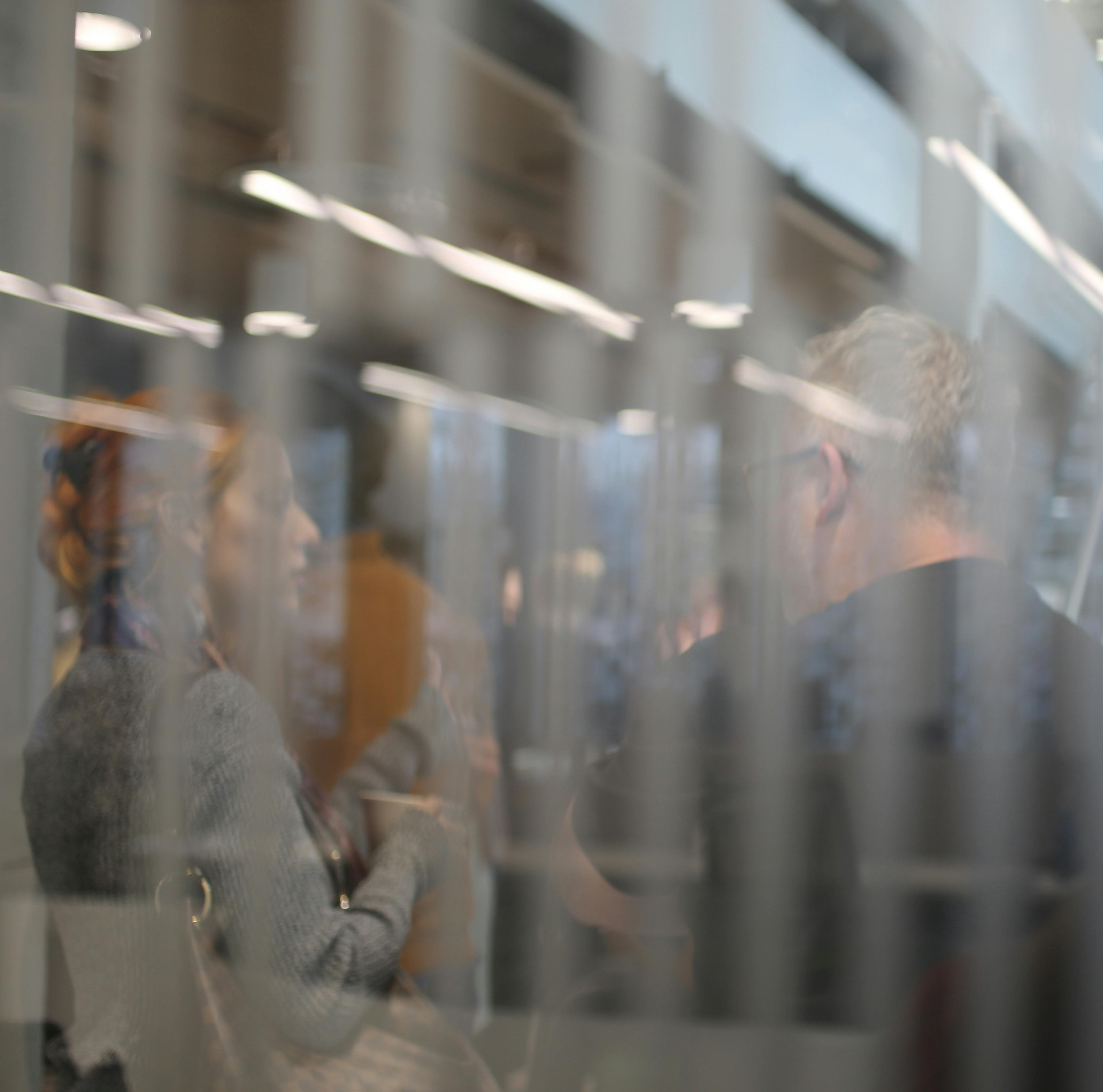 People speaking whilst behind a pane of glass