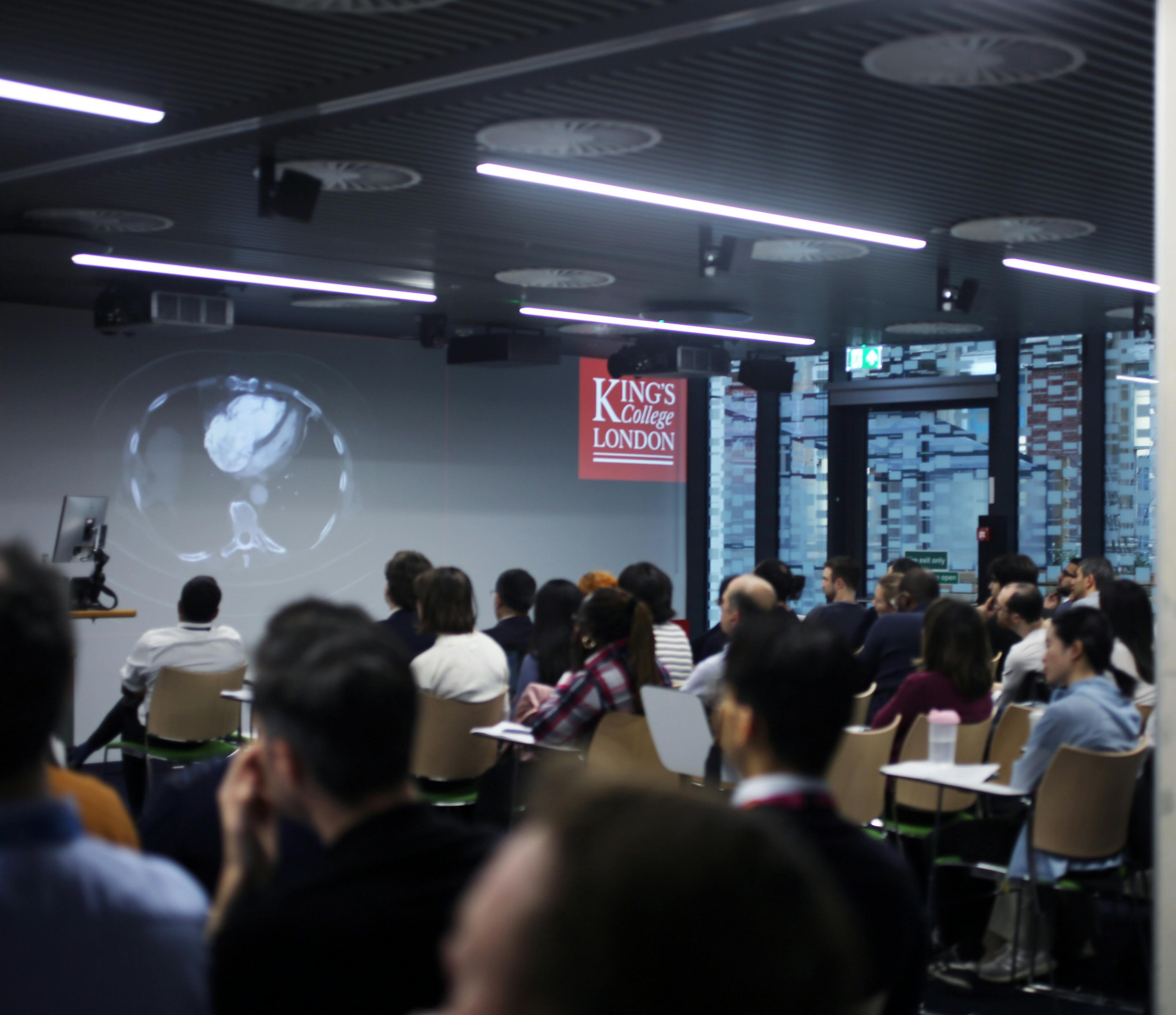 A theatre with a large group of people watching a lecture