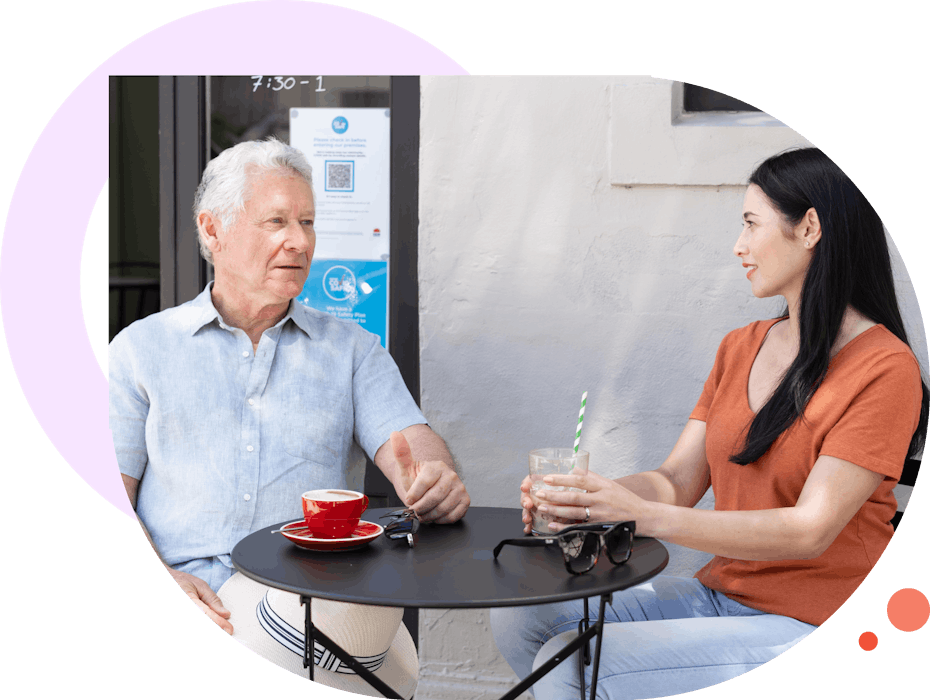 A Like Family Social Carer and an elderly Member enjoying a coffee at a cafe outdoors