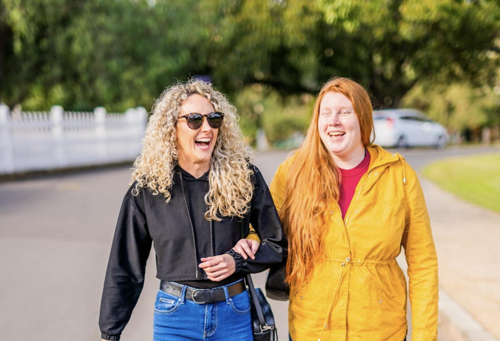A Like Family Social Carer and Member with their arms linked walking down a street