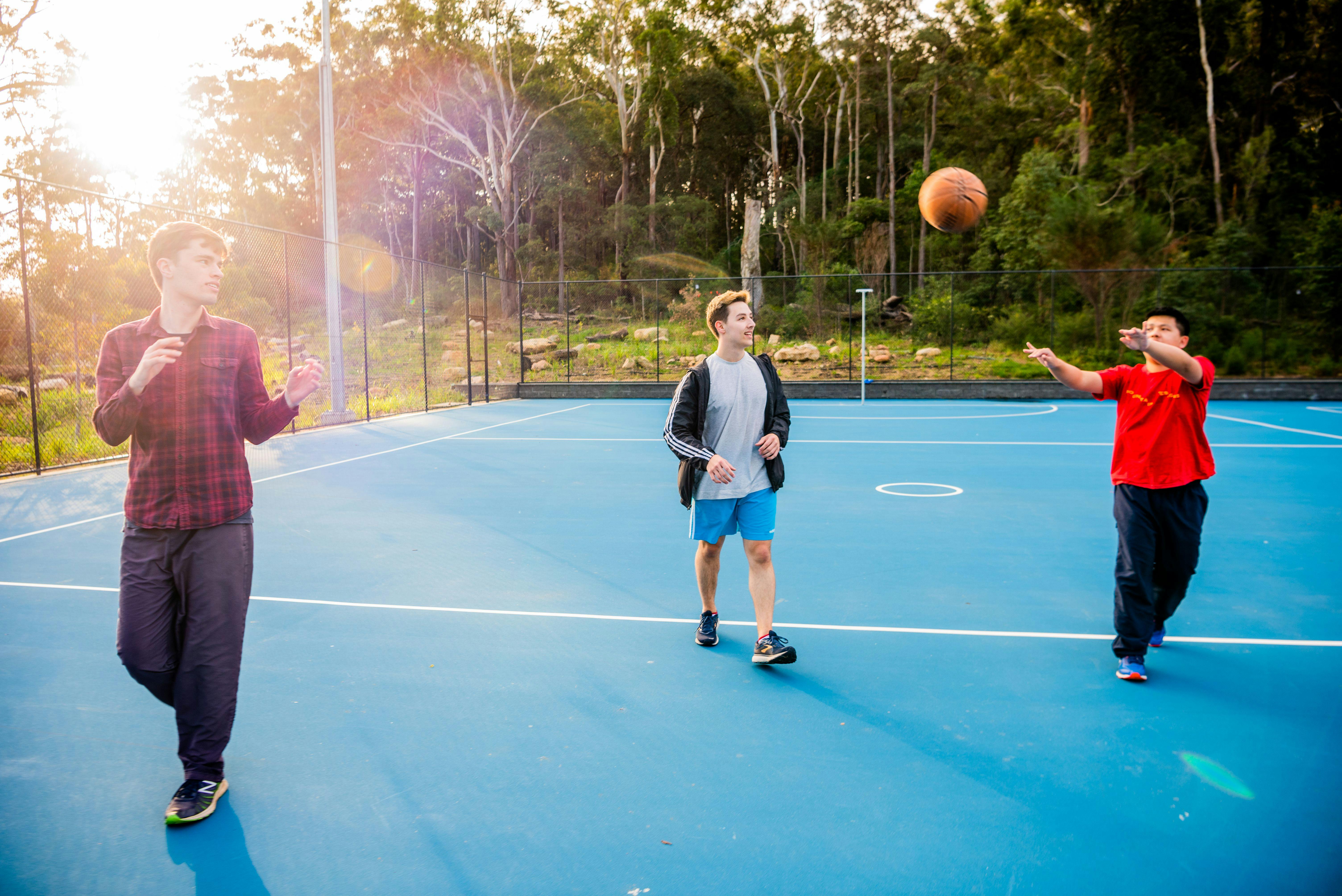 3 men playing basketball on a blue court