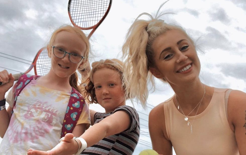 A Social Carer and her two young Members holding tennis racquets
