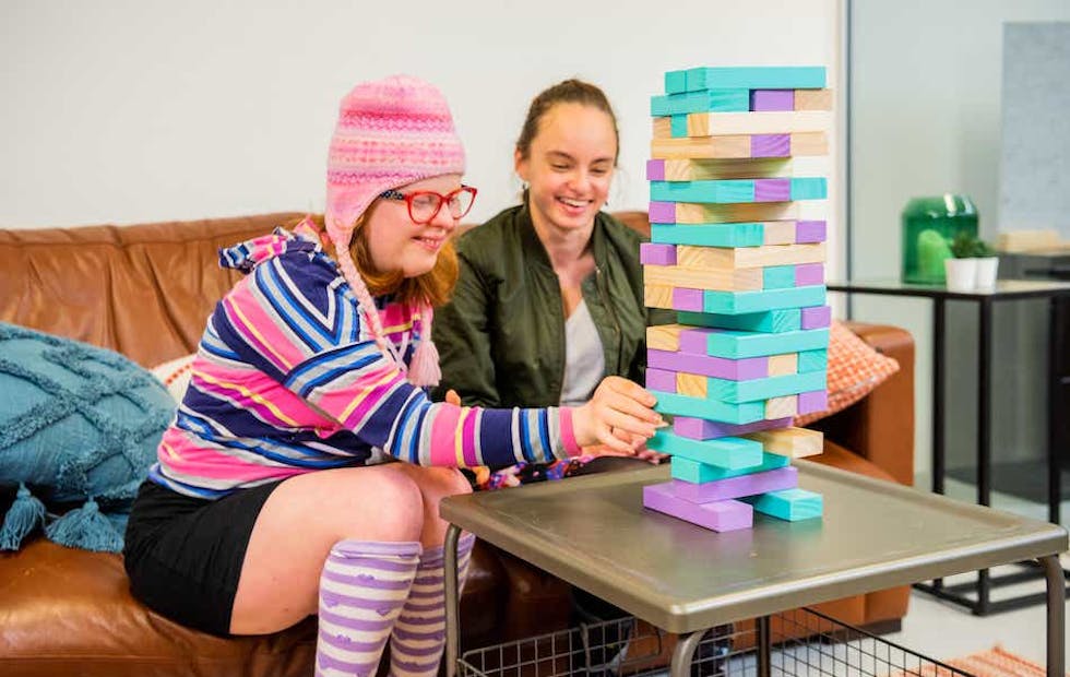 A Like Family Social Carer and Member playing Jenga with colourful blocks