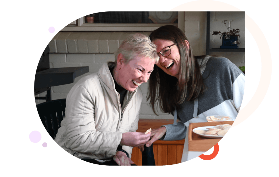 Two women laughing while enjoying afternoon tea together