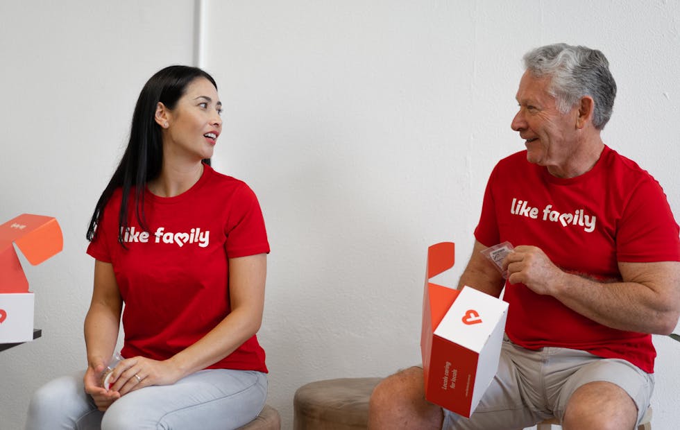 Two people in red Like Family t-shirts chatting