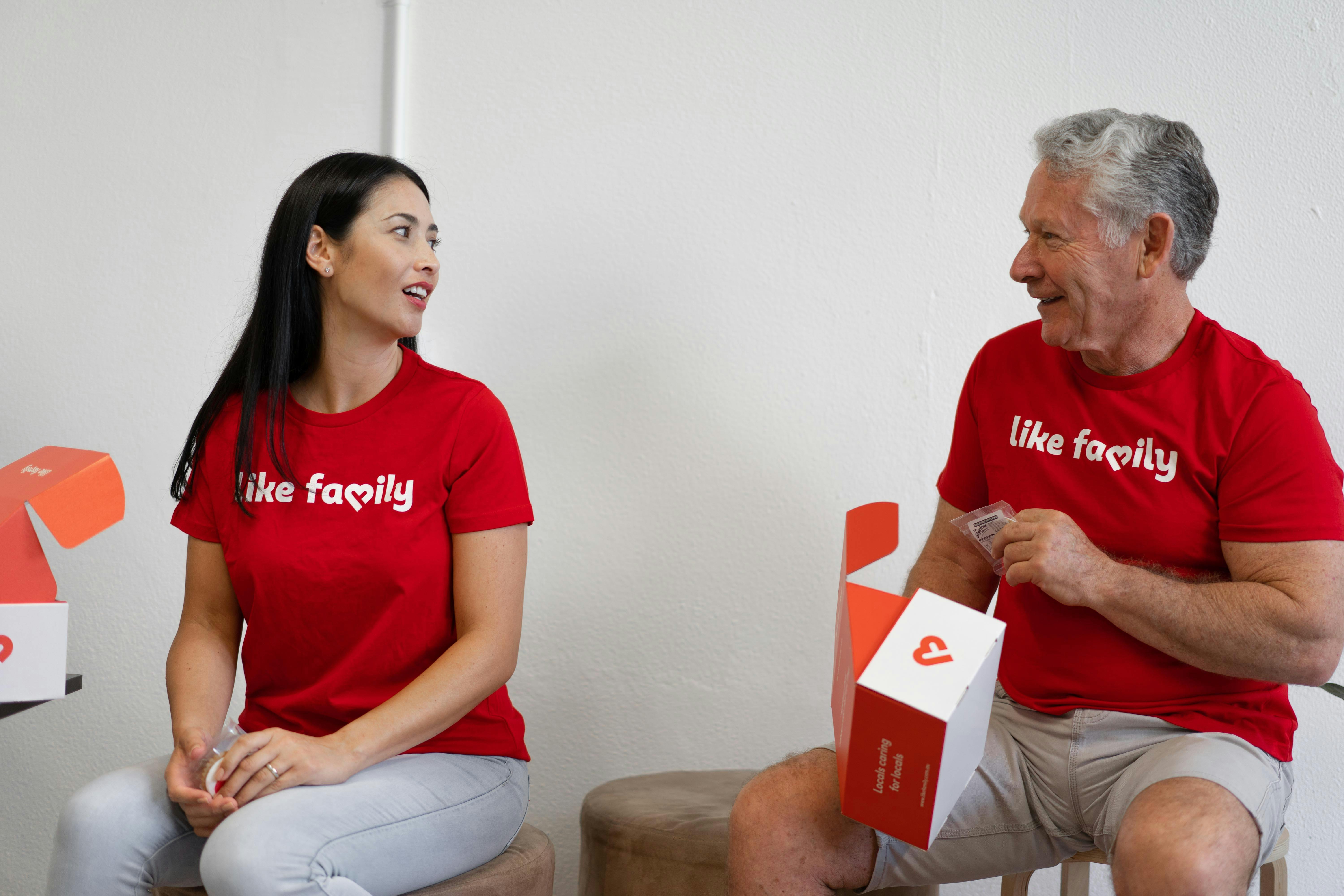 Two people wearing red Like Family t-shirts