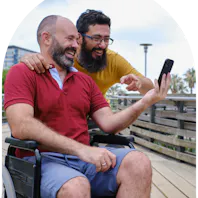 Member and carer looking at a phone outdoors