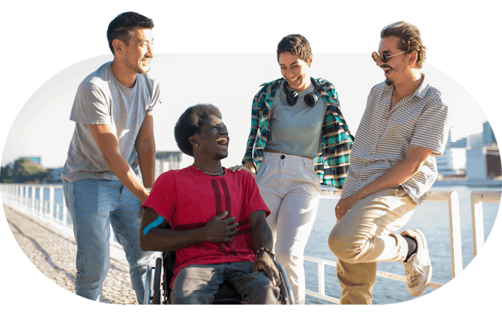 Support workers talking and laughing alongside a member on a seaside walk