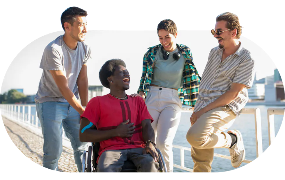 Support workers talking and laughing alongside a member on a seaside walk