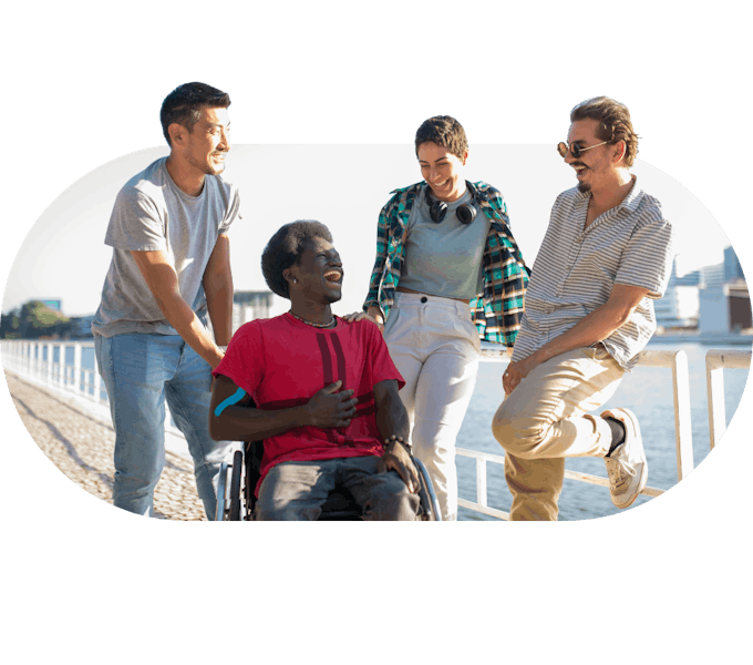 Support workers talking and laughing alongside a member on a seaside walk