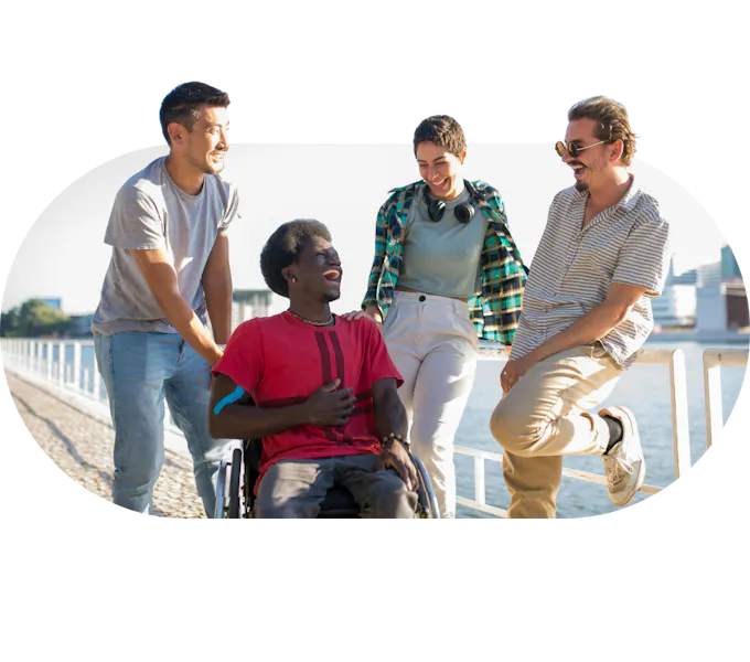 Support workers talking and laughing alongside a member on a seaside walk