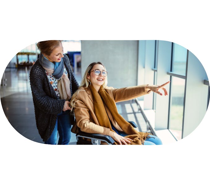 Support worker assisting a member in a wheelchair pointing out a window