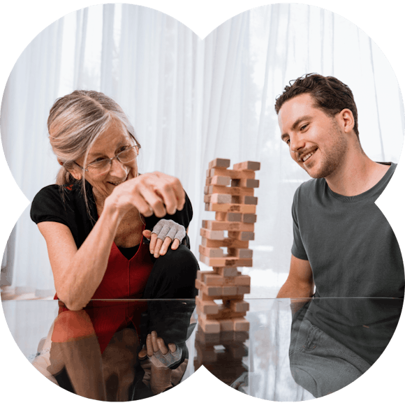 An elderly lady playing jenga with a social carer