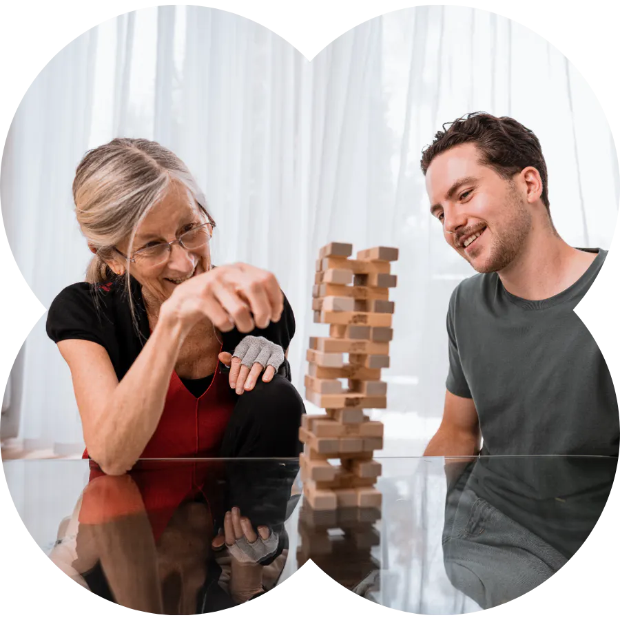 An elderly lady playing jenga with a social carer