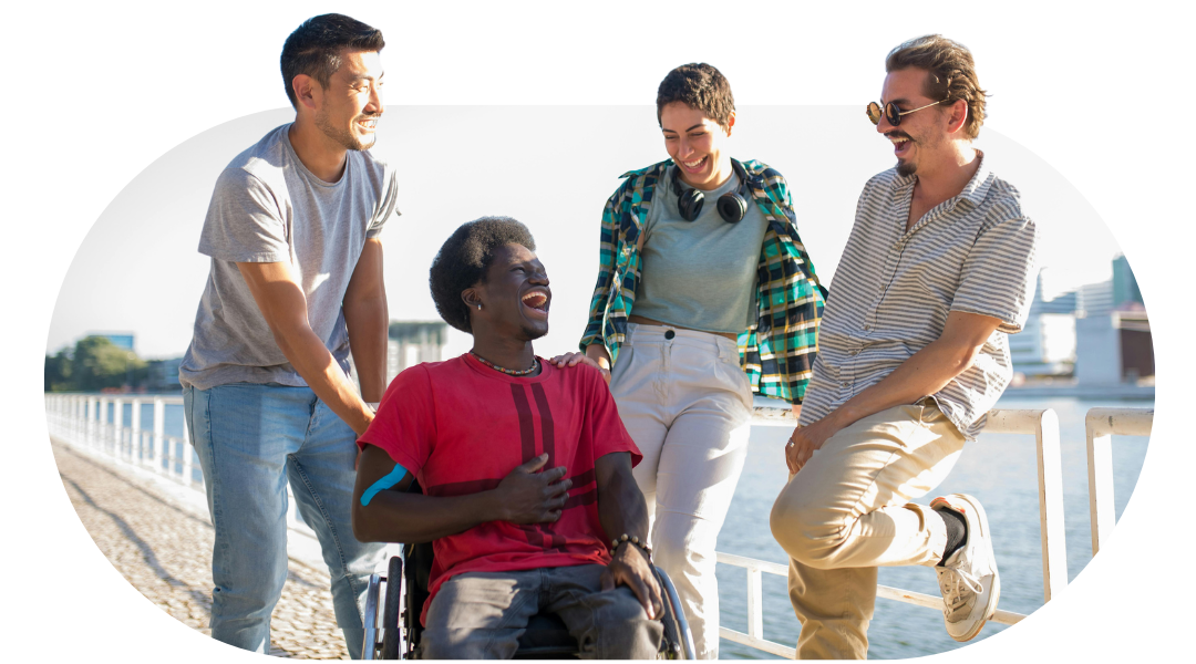 Support workers talking and laughing alongside a member on a seaside walk