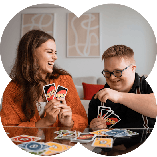 A support worker and member laughing while playing cards