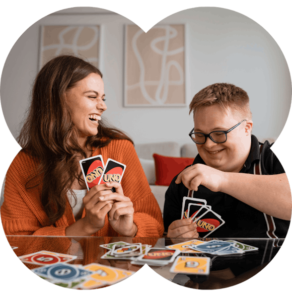 A support worker and member laughing while playing cards