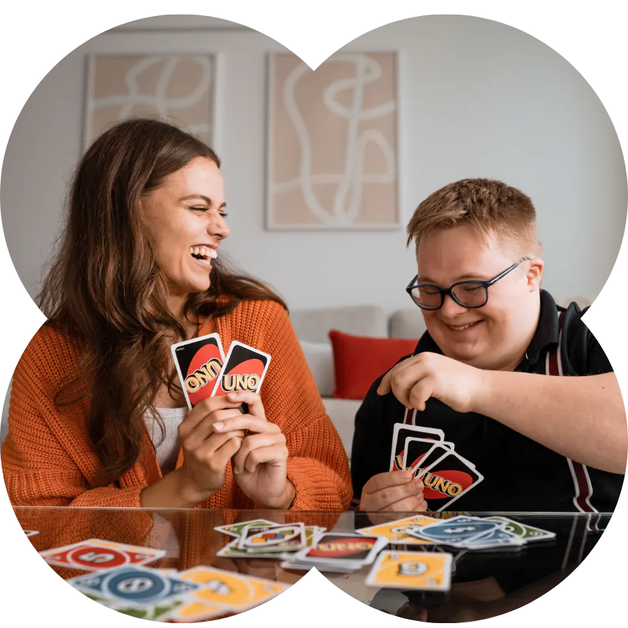 A support worker and member laughing while playing cards