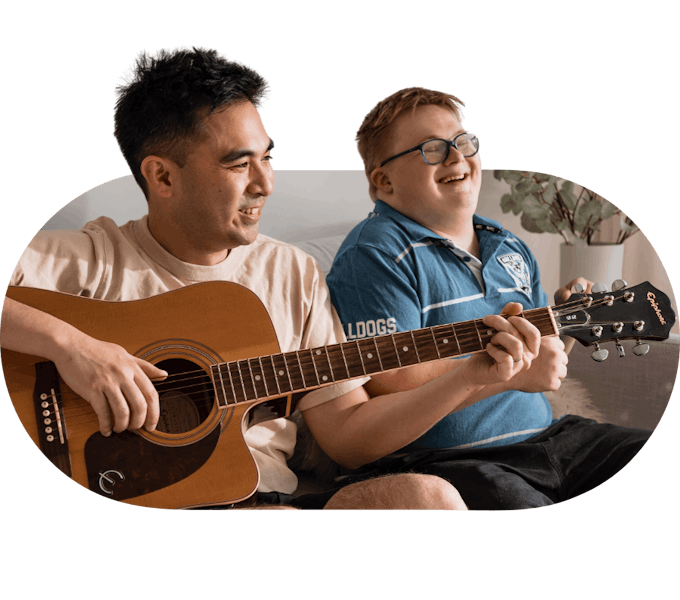 Support worker playing guitar with a young member enjoying the music
