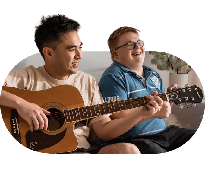 Support worker playing guitar with a young member enjoying the music