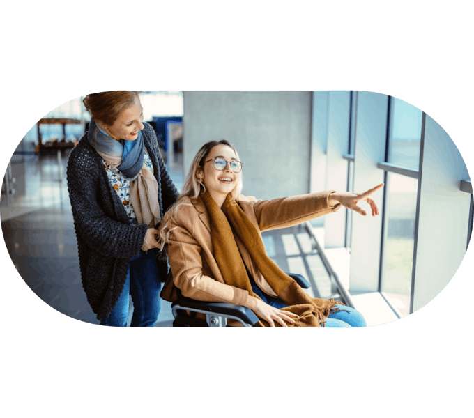 Support worker assisting a member in a wheelchair pointing out a window