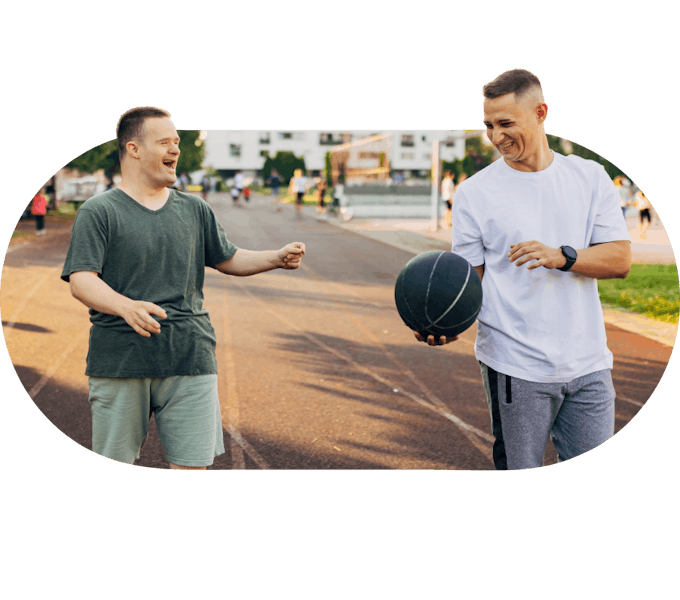 A member laughing with a Social Carer holding a basketball