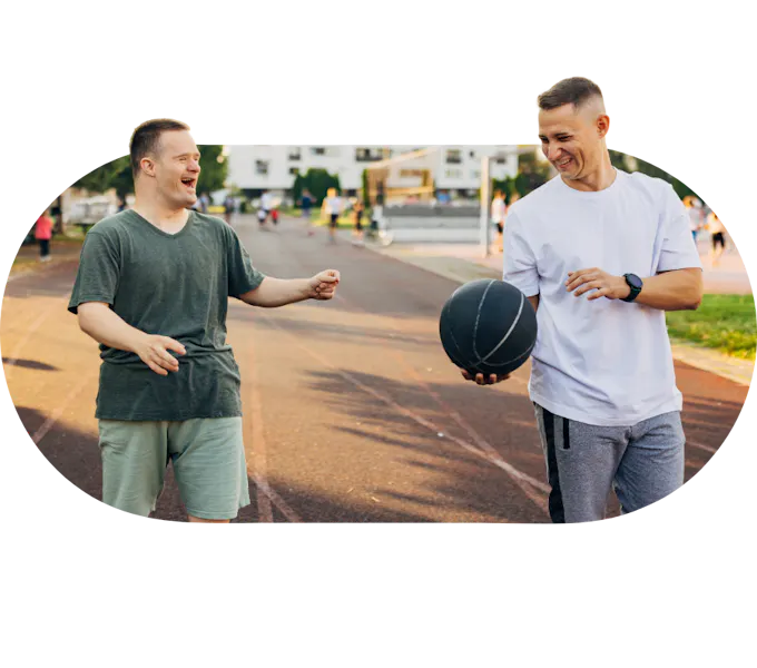 A member laughing with a Social Carer holding a basketball