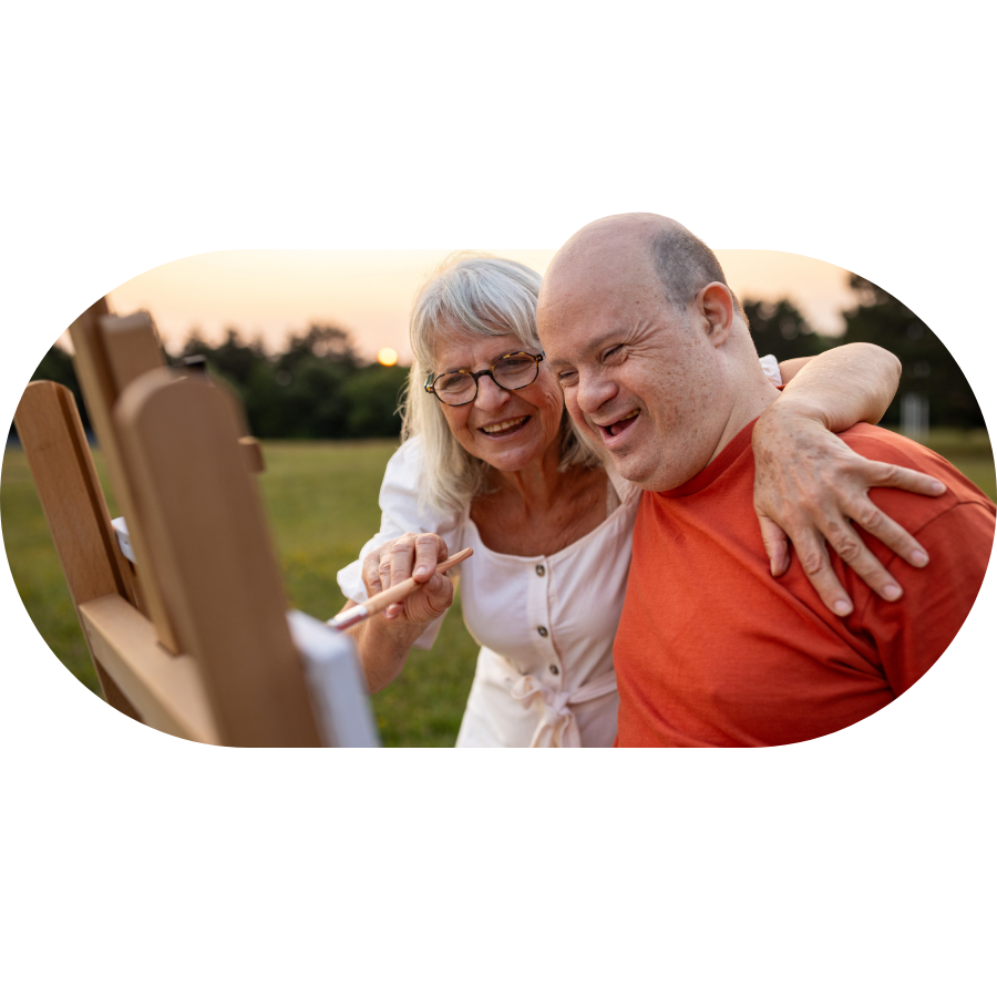 A Member and Carer smiling and painting together outdoors