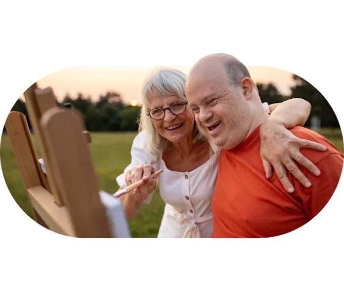A Member and Carer smiling and painting together outdoors