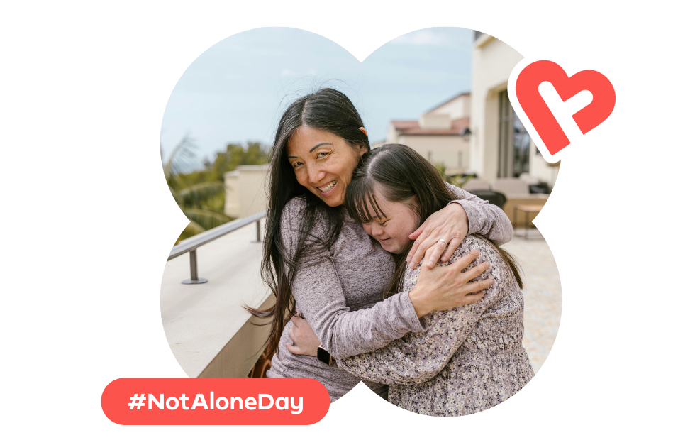 Two females in a warm friendly embrace, with the hashtag #NotAloneDay