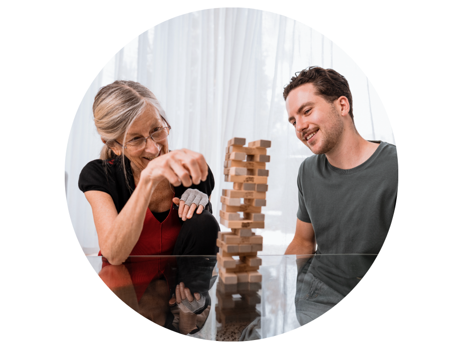 A a male support worker and older lady playing Jenga together