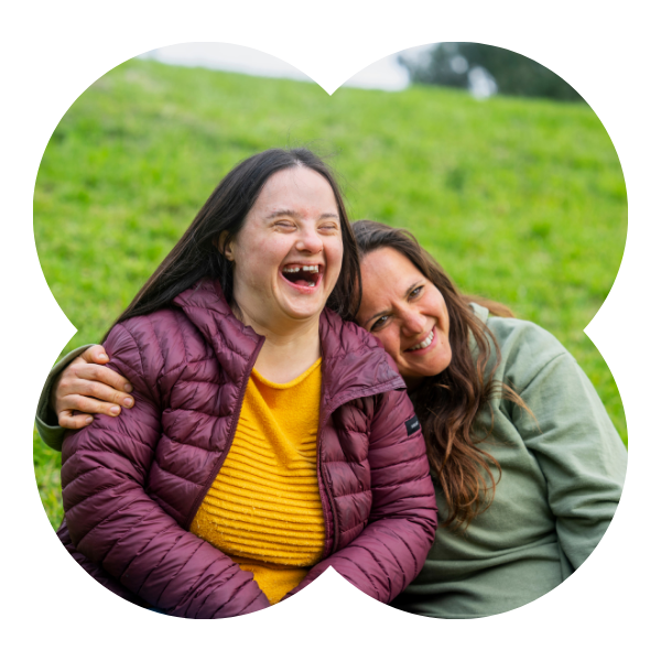 A Member and Social Carer smiling outdoors sitting on grass