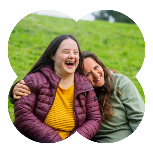 A Member and Social Carer smiling outdoors sitting on grass