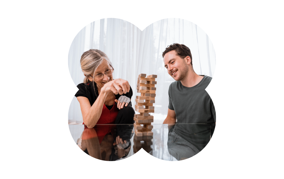 A Like Family Social Carer and older Member playing jenga together