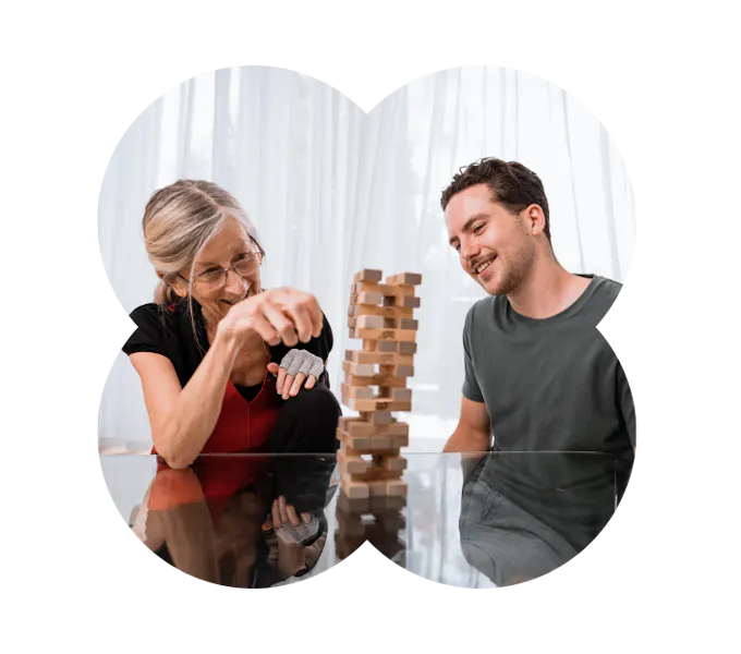 A Like Family Social Carer and older Member playing jenga together